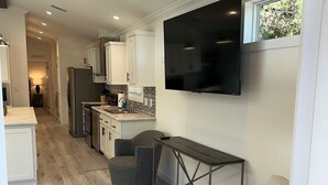 Uma cozinha moderna com armários brancos, forno embutido e uma televisão de tela plana instalada acima do balcão.