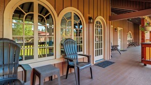 Un porche cubierto con piso de madera, ventanas arqueadas y mobiliario para exteriores.