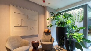 A modern interior with two armchairs, a coffee table, and a large potted plant. - Spodek Modern Apartment (Katowice)