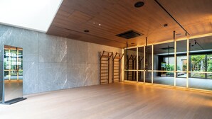 A spacious room with a wooden floor, a large window with a view of greenery, and a mirrored wall. - Spodek Modern Apartment (Katowice)