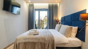 A hotel room with a large bed, a flat-screen TV mounted on the wall, and a view of the outdoors through a window. - Spodek Modern Apartment (Katowice)