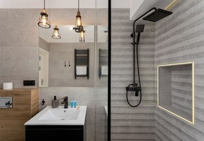 A modern bathroom with a white sink, wooden vanity, and a shower with a black hose. - Kraków Grzegórzki Deluxe Studio (Kraków)