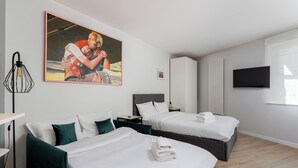 A hotel room with two beds, a painting, a TV, and a bedside table. - Kraków Grzegórzki Deluxe Studio (Kraków)