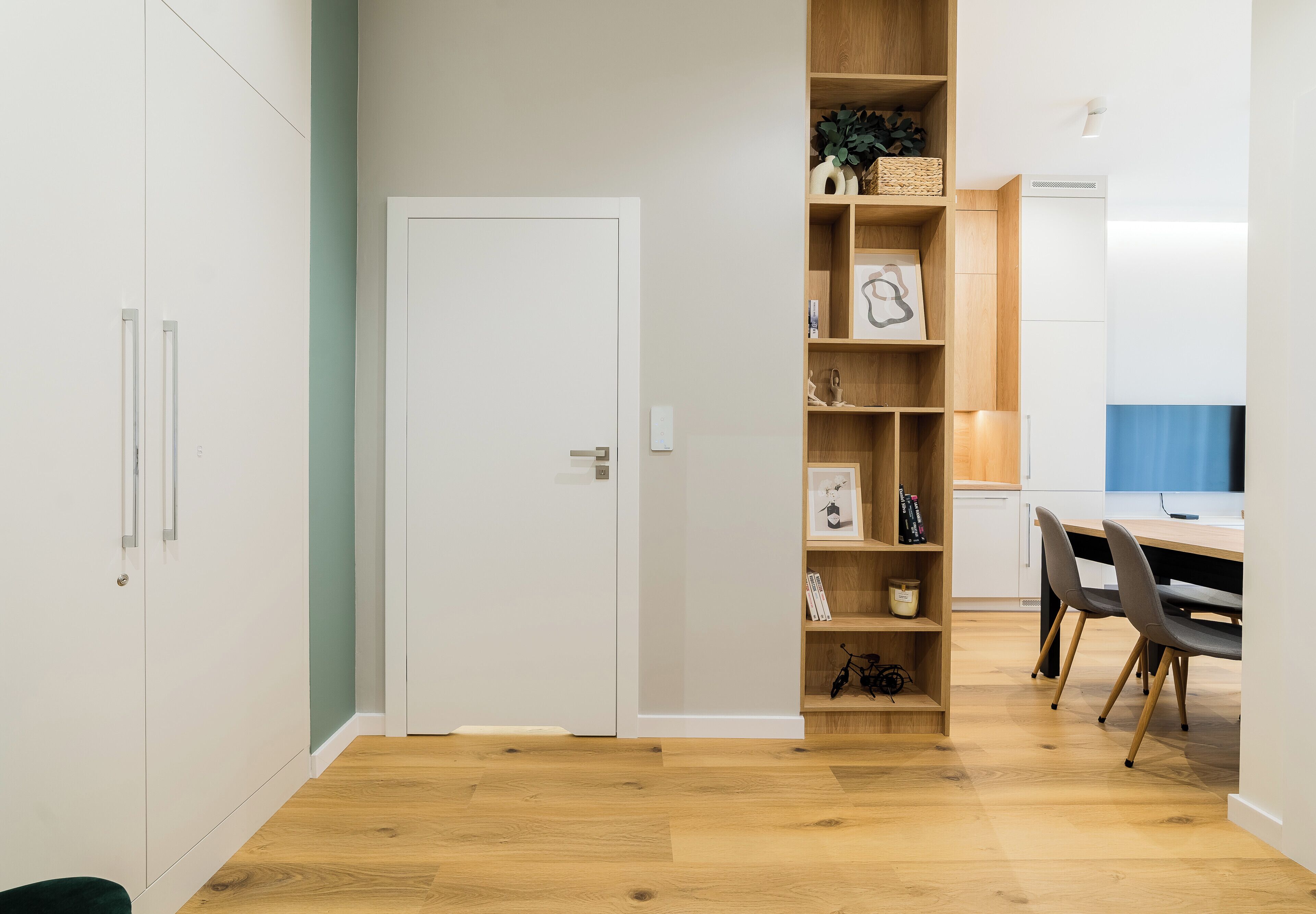 A modern kitchen with wooden shelves, a dining table, and chairs.