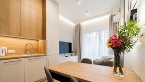 Une cuisine moderne avec des meubles en bois, un four encastré et un coin repas comprenant une table et des chaises en bois.