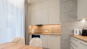 Eine moderne Küche mit Esstisch aus Holz, weißen Schränken und einem eingebauten Geschirrspüler.