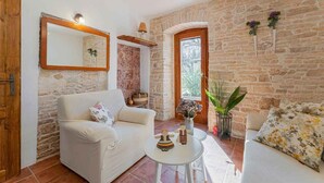 Uma sala de estar acolhedora com uma parede de pedra, um sofá branco, uma mesa de centro e uma porta de madeira.