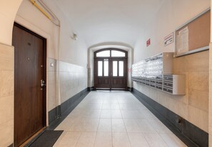 A hallway with a wooden door, a double door at the end, and a row of lockers on the right. - Bocheńska Modern Apartment (Kraków)
