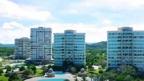 Een hoog hotel met meerdere verdiepingen, omringd door weelderige begroeiing en een heldere lucht.