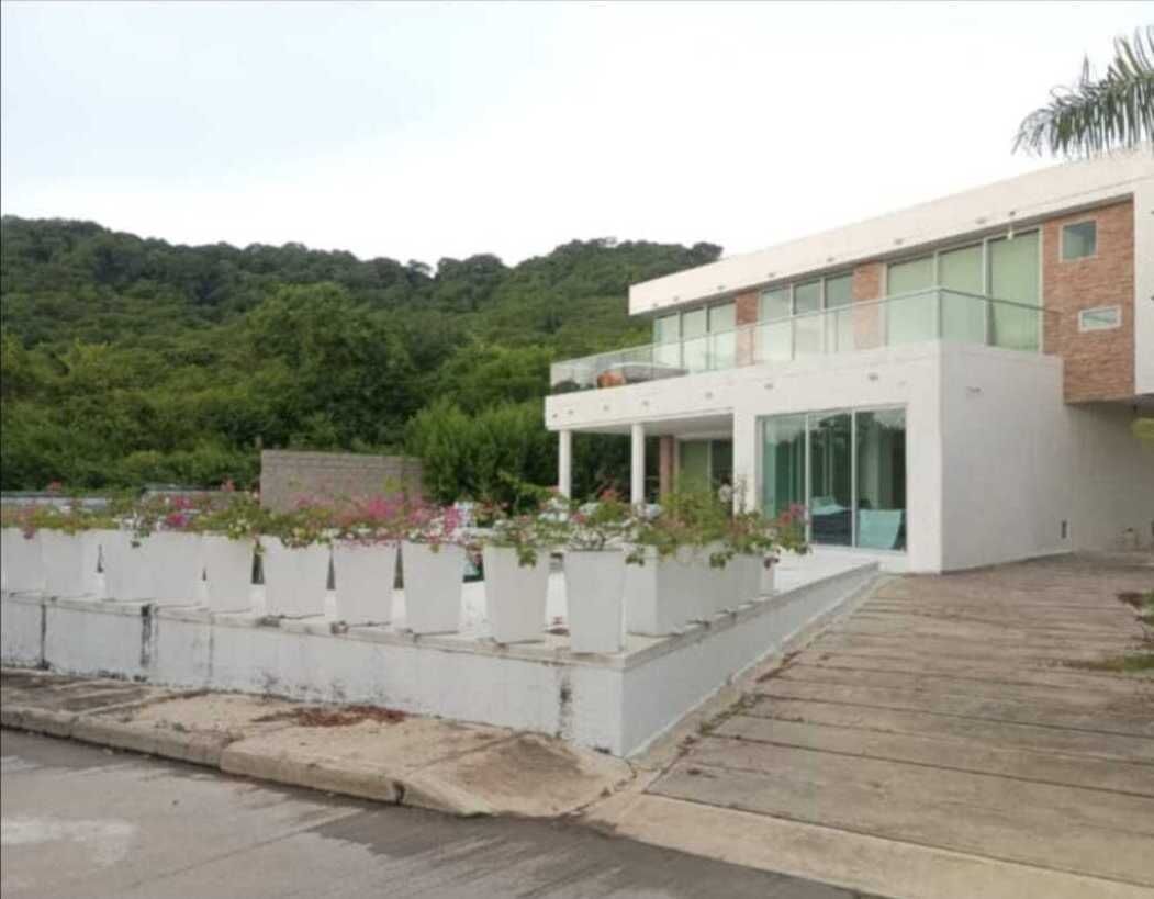 A modern building with a flat roof, large windows, and a paved entrance area with planters.