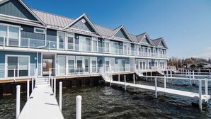 A waterfront hotel with multiple balconies, a dock, and a clear view of the water. - Chic Lakefront Getaway W/ Hot tub + Kayaks! (Alanson)