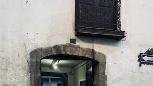 An arched entrance to a building with stone walls and a cobblestone street. - Hostal Tres Reyes (Cusco)