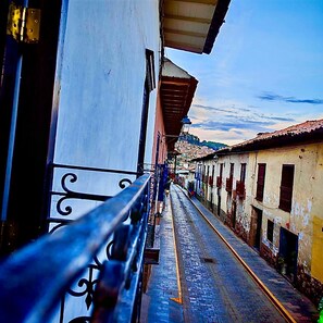 A narrow street with buildings on either side, a metal railing, and a clear sky. - Alojamiento en Casona Colonial Céntrica (Cusco)