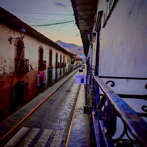 A narrow street with buildings on either side, a sign for a hospital, and a train track. - Alojamiento en Casona Colonial Céntrica (Cusco)