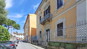 Un carrer amb edificis, una tanca de metall i cotxes aparcats.