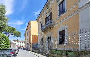 A street with buildings, a metal fence, and parked cars. - Amazing apartment in Pisa with WiFi (Pisa)
