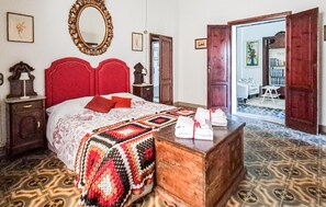 A bedroom with a red headboard, a patterned bedspread, a wooden dresser, and a mirror on the wall. - Amazing apartment in Pisa with WiFi (Pisa)