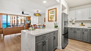 Una cocina moderna con armarios grises, una isla de mármol y un refrigerador grande.