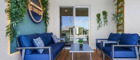 Un espace extérieur moderne, aménagé avec un canapé et des fauteuils bleus, une petite table et un panneau sur lequel on peut lire : « VOTRE HISTOIRE UNIQUE ».