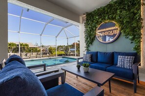 A poolside area with a blue sofa, a coffee table, and a view of a swimming pool.