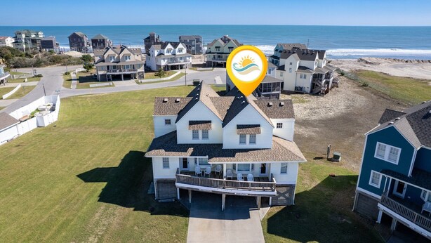 Una zona residenziale costiera con una casa ben visibile, dotata di un balcone e vista sull'oceano.