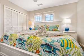 A bedroom with a bed, two windows, a nightstand, and a lamp. - Egret – Bright Buxton Townhome w/ Ocean Views (Buxton)