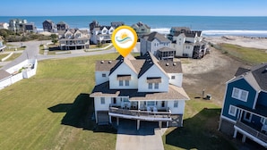Ein Küstenwohngebiet mit einem markanten Haus, das einen Balkon und Blick auf den Strand bietet.
