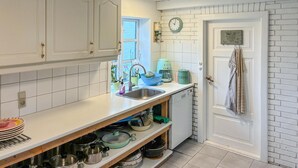 A kitchen with white cabinets, a sink, a clock, and a door with a towel hanging on it. - Beautiful home in Stege with WiFi (Stege)