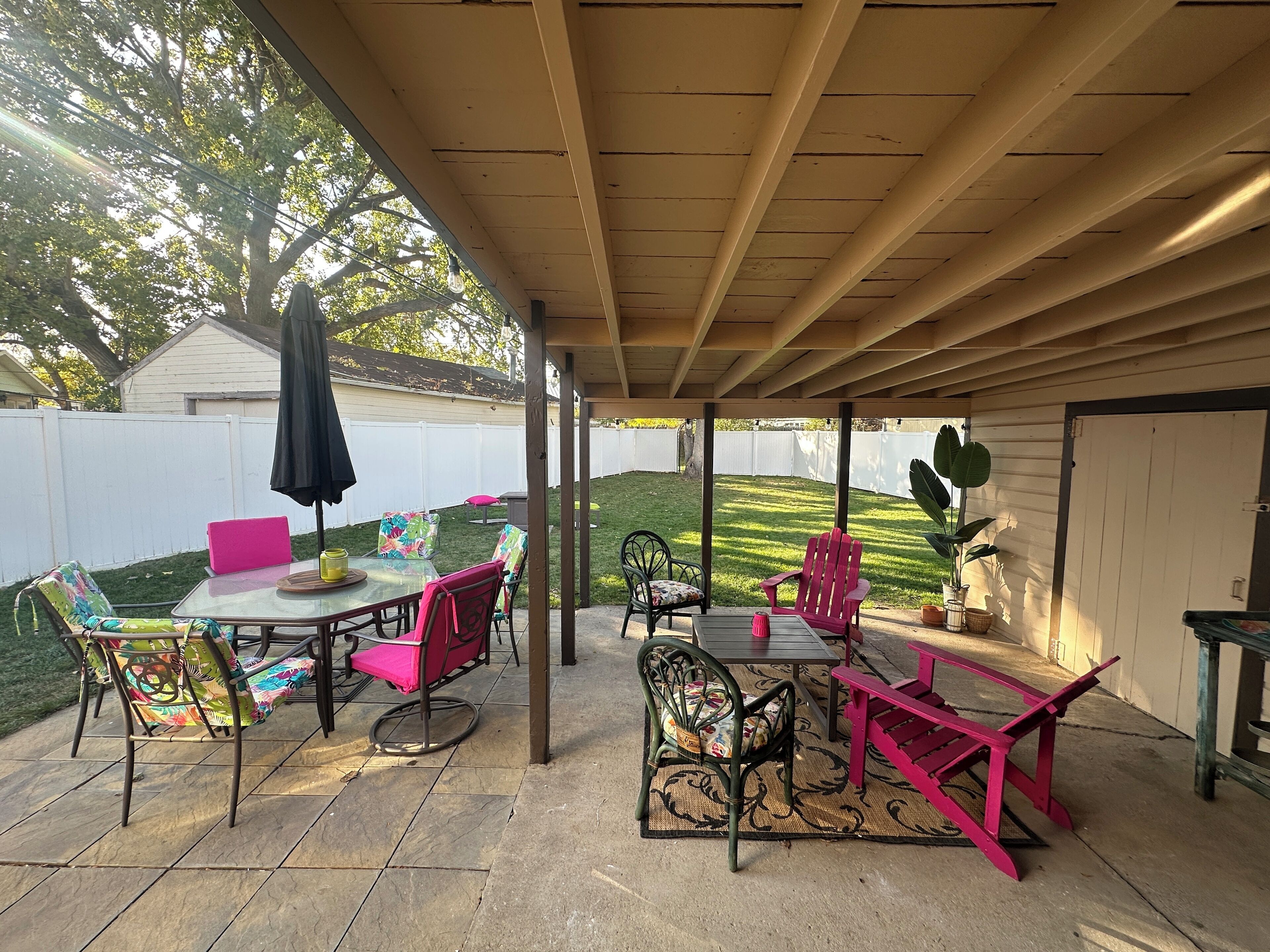 Une terrasse extérieure dotée d’un espace salon abrité, d’une table et de chaises.