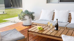 A wooden deck with a sofa and chairs, a table with a bottle and glasses, and a potted plant. - Palm Beach Family Retreat (Palm Beach)