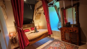 A cozy bedroom with a sloped ceiling, a bed with red pillows, a wooden dresser, and a large mirror. - Paradise lost swimming pool jacuzzi billiards table soccer... (Louvie-Juzon)