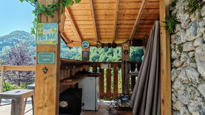 A wooden hut with a stone wall, a wooden ceiling, and a sign for a tiki bar. - Paradise lost swimming pool jacuzzi billiards table soccer... (Louvie-Juzon)