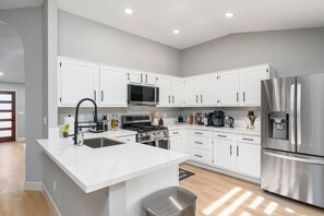 Una cocina moderna con armarios blancos, electrodomésticos de acero inoxidable y una isla central.