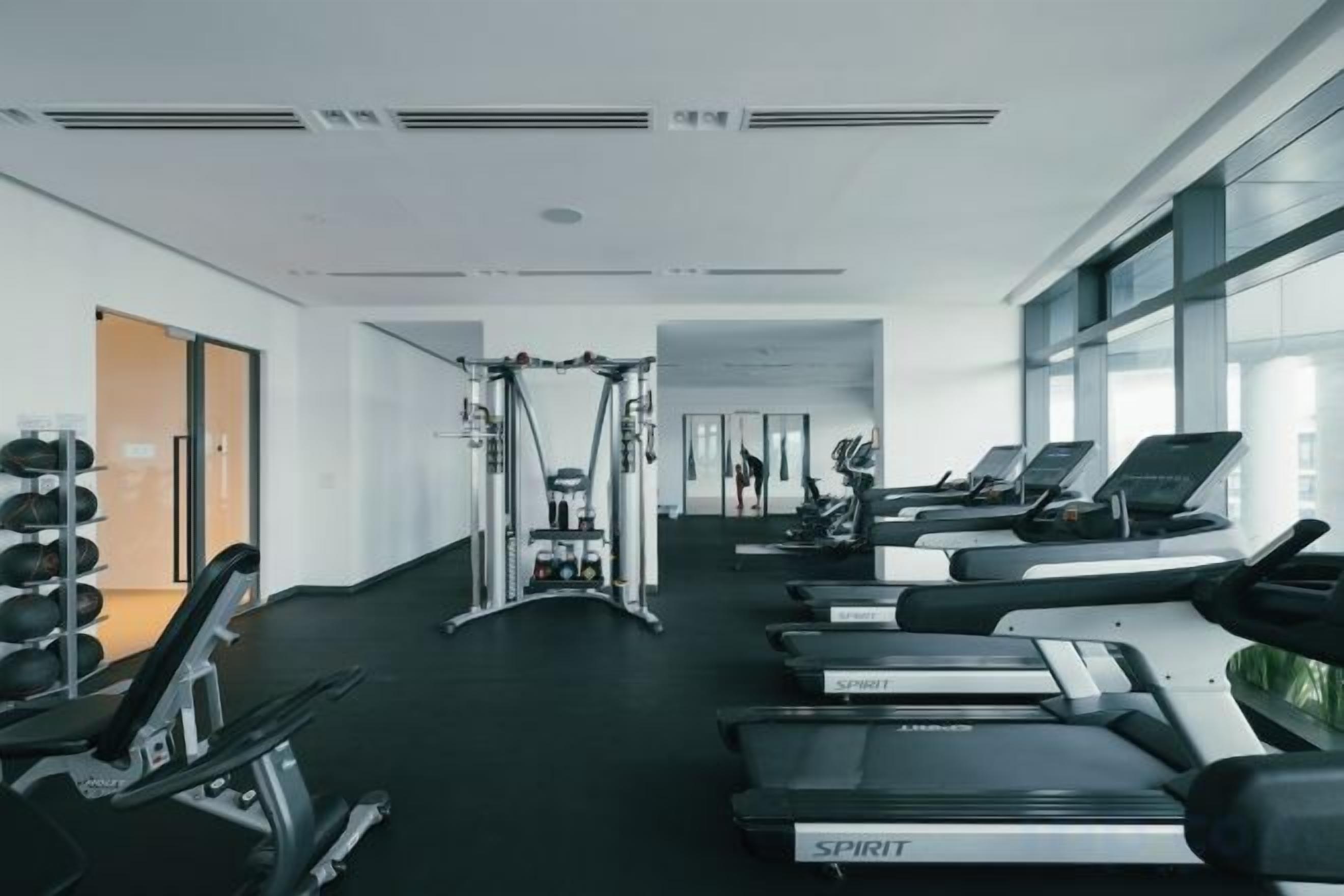 A gym with treadmills, weight machines, and a mirror.
