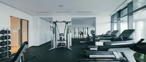 A gym with treadmills, weight machines, and a mirror.