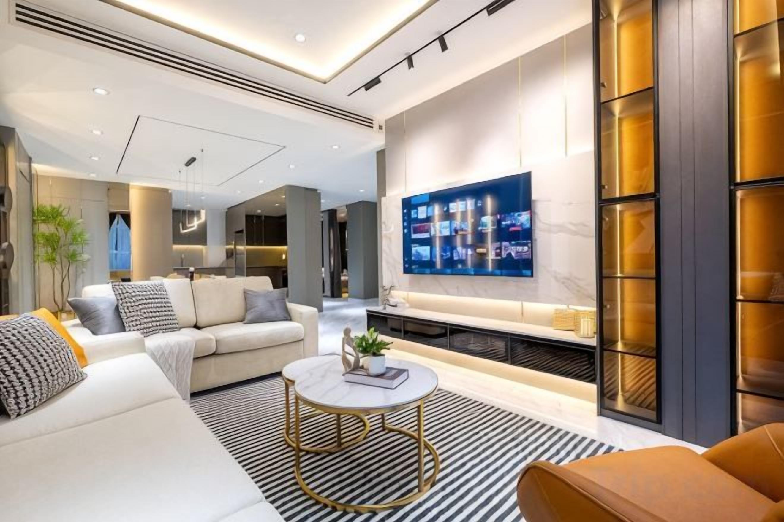 A modern living room with a sofa, coffee table, and a flat-screen TV mounted on the wall.