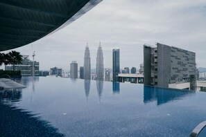 An infinity pool with a view of the Petronas Towers and surrounding modern buildings. - EATON BY FEEL HOME (Kuala Lumpur)