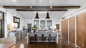 Une cuisine spacieuse dotée d’un grand îlot central, de meubles en bois et de luminaires suspendus.