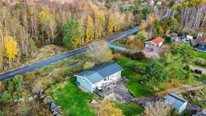 Vue aérienne d’un quartier résidentiel comprenant une maison principale, un petit abri de jardin et une route.
