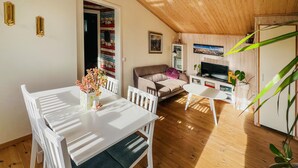 Un salon confortable avec un canapé, un téléviseur et un coin repas comprenant une table et des chaises.