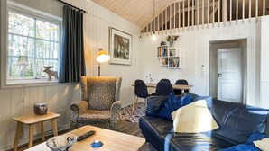 A cozy living room with a patterned armchair, a leather sofa, a small table with a remote control, and a bookshelf. - Nice home in Svanskog with WiFi (Svanskog)
