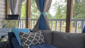 Eine überdachte Veranda mit bequemen Sitzgelegenheiten, einem Sessel und Blick ins Grüne.