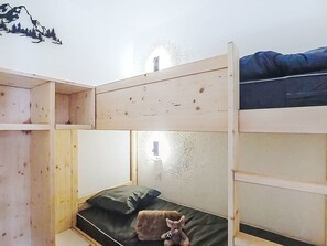 A bunk bed room with a wooden bunk bed, a single bed below, and a wall decal of a mountain. - Les Olympiades by Interhome (Val Thorens)
