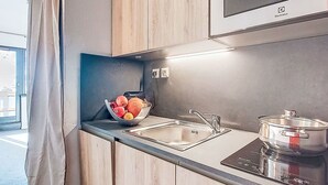 Eine moderne Küche mit Holzschränken, einer Edelstahlspüle, einer Obstschale und einem Induktionskochfeld.
