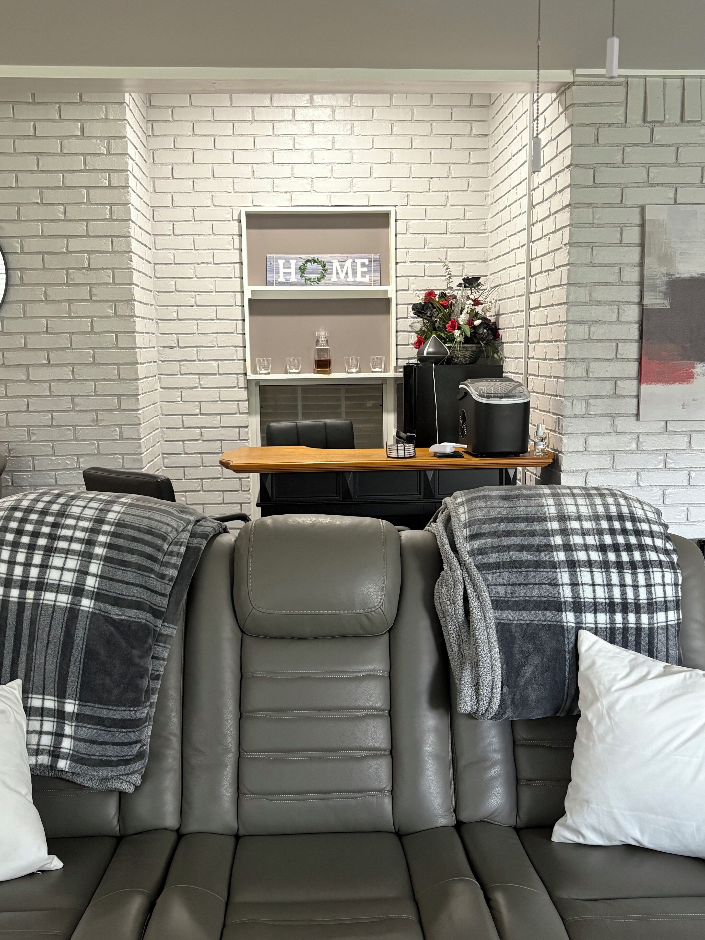 Ein modernes Wohnzimmer mit einer Couch, einem Couchtisch und einem Kamin. Zwei Sessel und ein kleiner Tisch mit Blumenvase sind ebenfalls vorhanden.