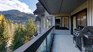 Un balcone con una griglia e vista su una catena montuosa ricoperta da una fitta vegetazione.