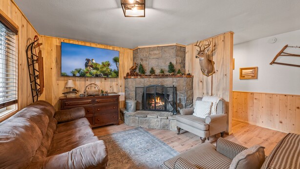 Ein gemütliches Wohnzimmer mit Kamin aus Stein, Holzwänden und einem aufgehängten Hirschkopf.