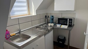 A compact kitchen with a sink, stove, and microwave. - Comfort Appart 3 (Calais)