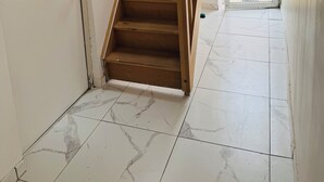 A staircase with wooden steps and a metal railing, leading to an open door. - Comfort Appart 3 (Calais)