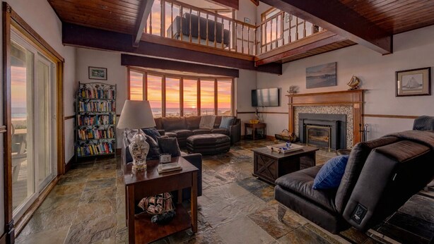 A spacious living room with a fireplace, a balcony, and a bookshelf. - Serenity at South Beach (Westport)